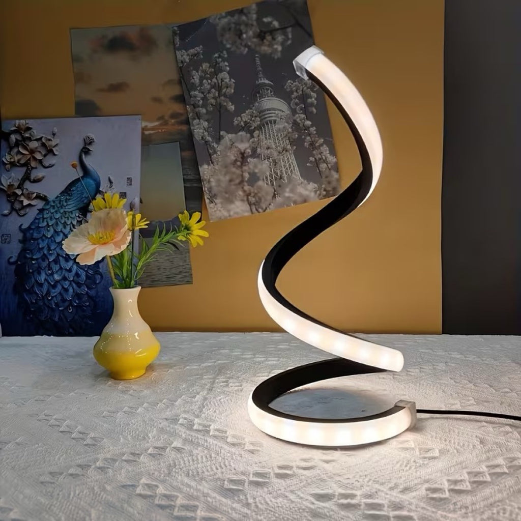 Black spiral LED lamp on a table with a vase