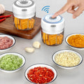Electric mini food chopper with bowls of chopped vegetables and garlic